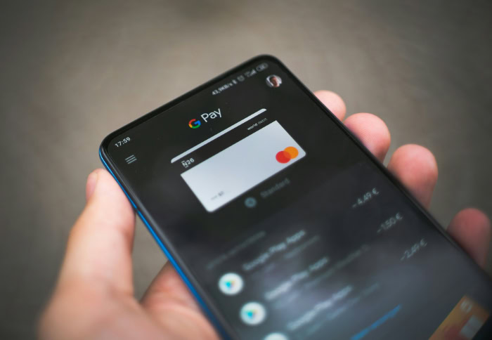 Hand holding phone showing Google Pay payment card