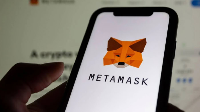 Hand holding phone with MetaMask wallet app