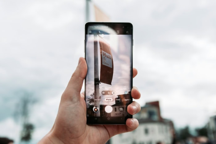 Hand holding smartphone capturing photo of outdoor building sign