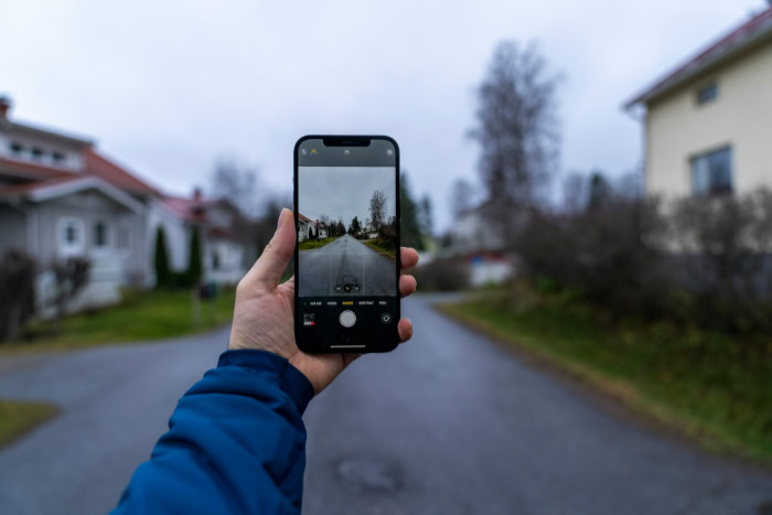 Hand holding smartphone capturing quiet suburban street view