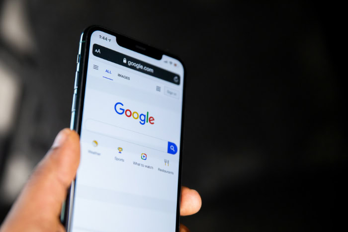 Hand holding smartphone displaying Google mobile search page
