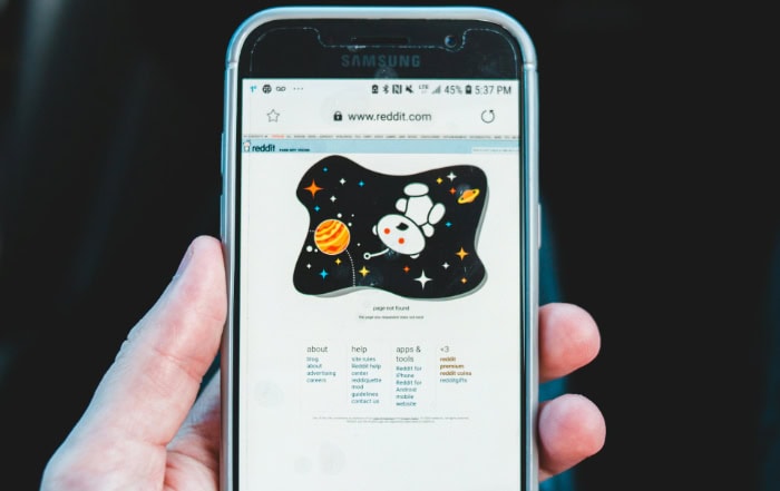 Hand holding smartphone displaying Reddit homepage