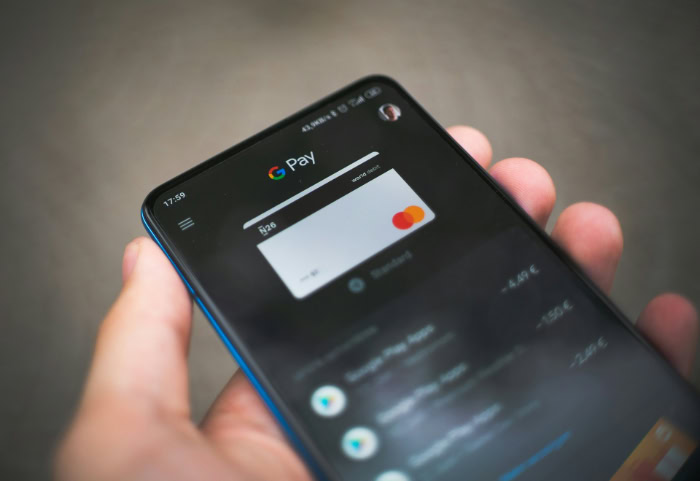 Hand holding smartphone showing Google Pay with Mastercard