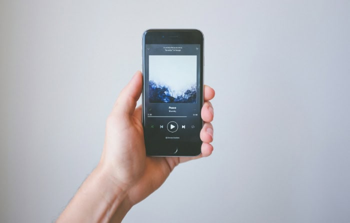 Hand holding smartphone showing Spotify app