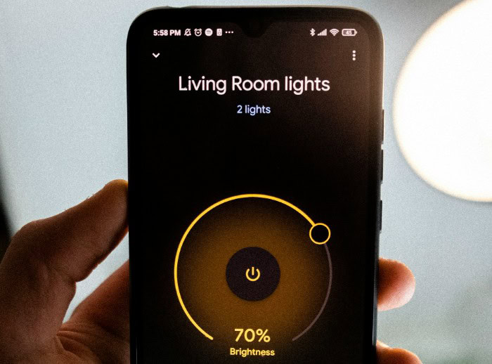 Hand holding smartphone to control smart home lighting