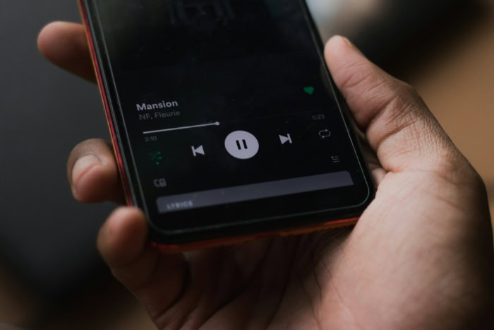 Hand holding smartphone with paused music player