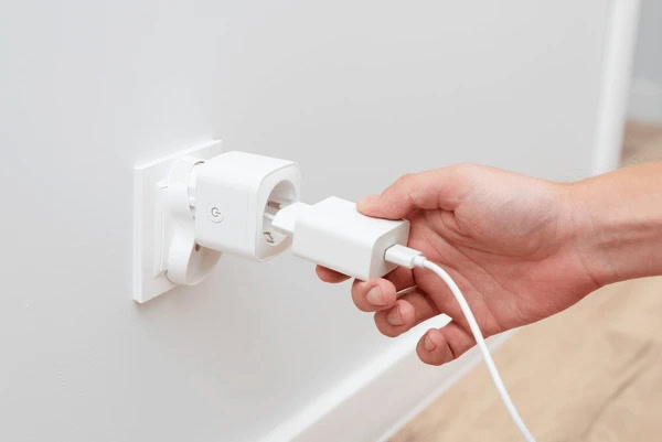 Hand plugging phone charger into smart plug