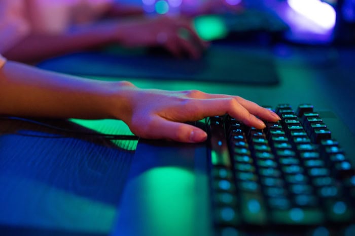 Hand positioned on a gaming keyboard in dim lighting