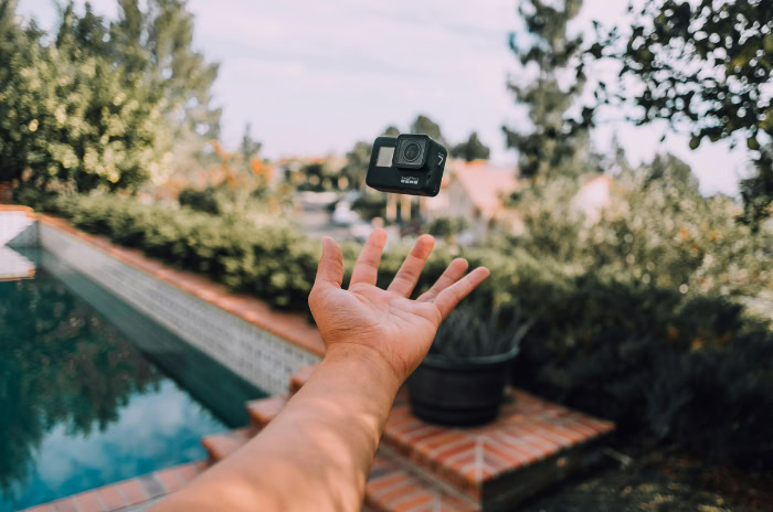 Hand tossing GoPro camera outdoors by a pool