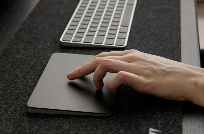 Hand using a trackpad next to a keyboard