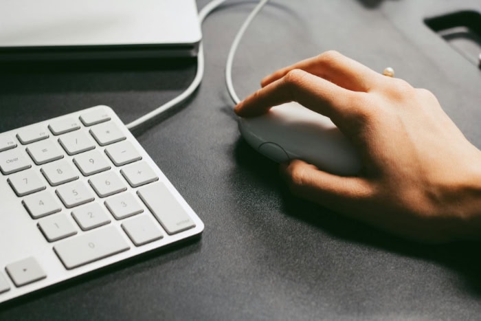 Hand using white mouse next to numeric keypad