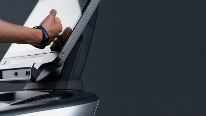 Hand with fitness tracker tapping exercise machine touchscreen