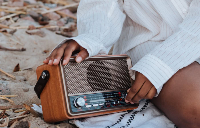 Hands adjusting vintage wooden radio on sandy beach