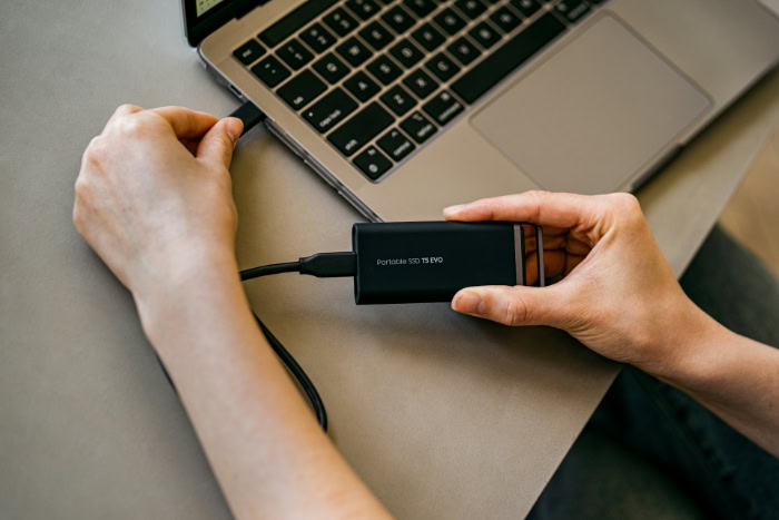 Hands connecting Samsung T5 EVO SSD to laptop