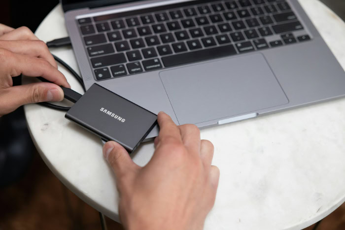 Hands connecting Samsung portable SSD to a laptop