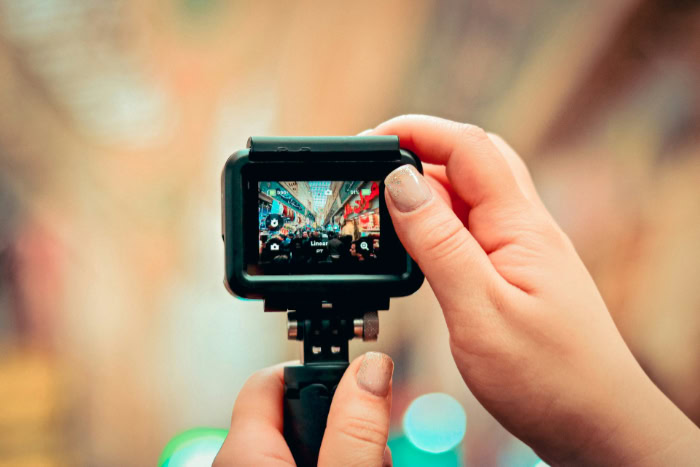 Hands holding GoPro showing street market on screen