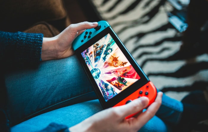 Hands holding Nintendo Switch console displaying colorful game