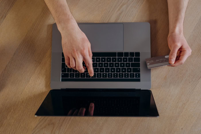 Hands holding a credit card while using a laptop