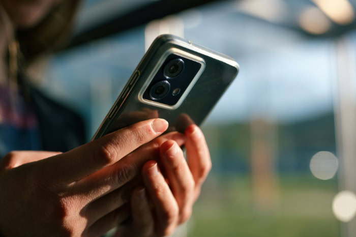 Hands holding a dual camera smartphone in natural light