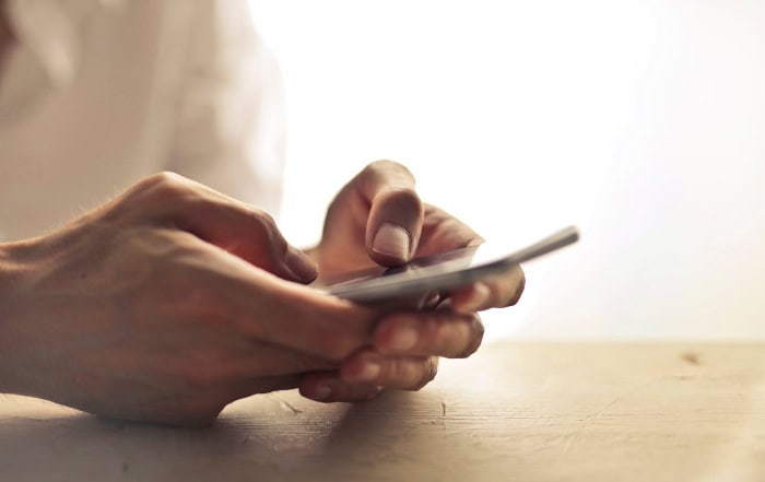 Hands holding and using smartphone on wooden surface