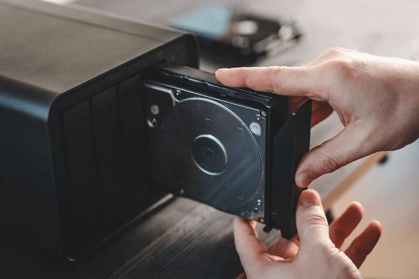 Hands pulling a hard drive tray out of NAS resized