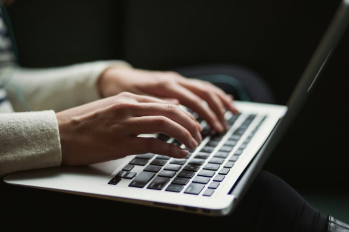 Hands typing on MacBook keyboard in soft lighting