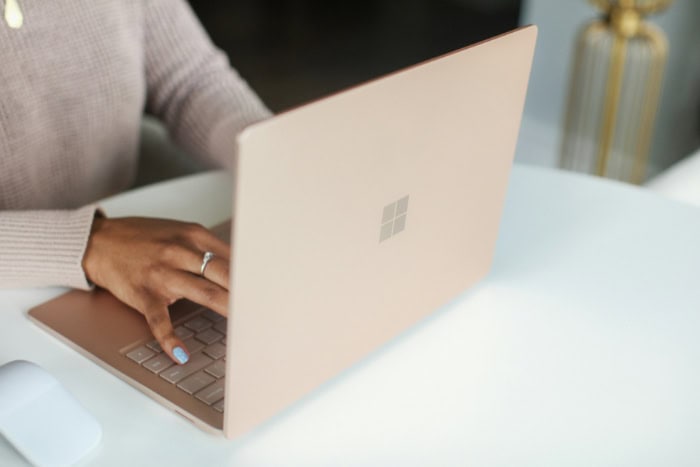 Hands typing on Microsoft Surface laptop in rose gold