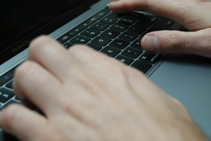 Hands typing on a MacBook Pro keyboard