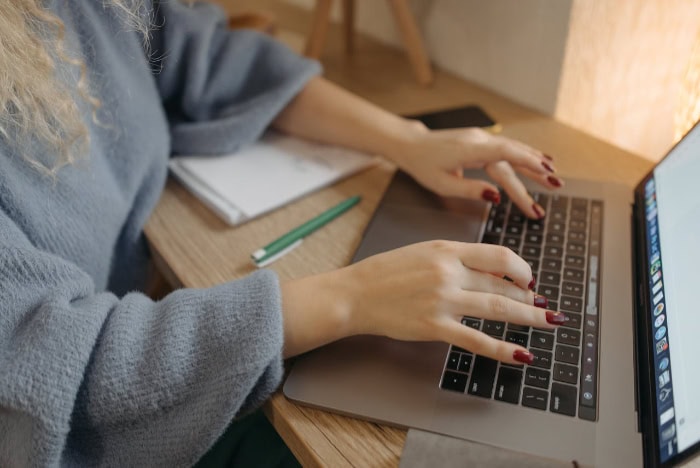 Hands typing on a laptop at a desk