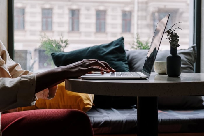 Hands typing on a laptop in a cozy cafe