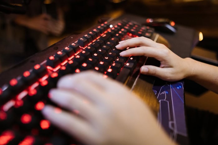 Hands typing on illuminated gaming keyboard