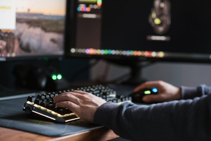 Hands typing on illuminated keyboard