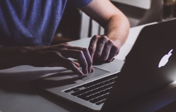 Hands typing on laptop keyboard in dim lighting