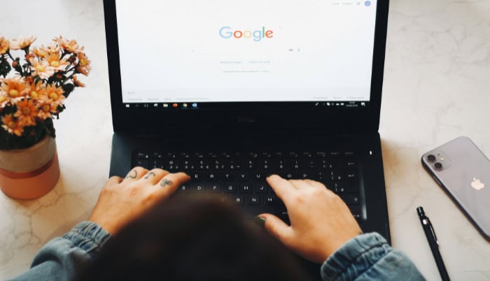 Hands typing on laptop with Google homepage
