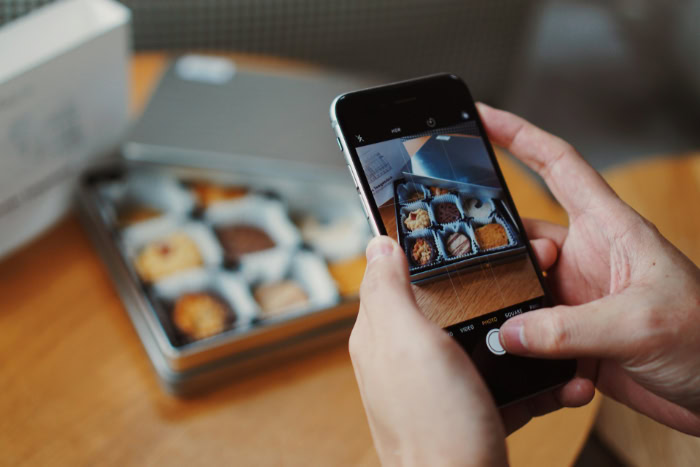 Hands using smartphone to photograph a box of cookies