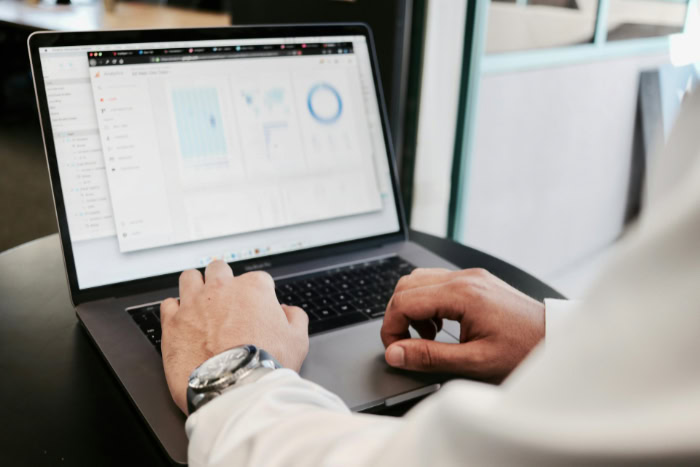 Hands working on laptop with analytics dashboard