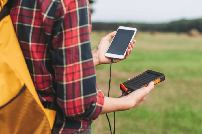 Hiker charging phone with solar power bank outdoors