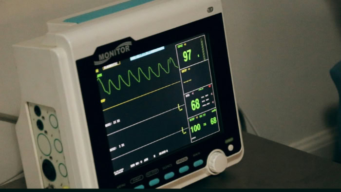 Hospital patient vital signs monitor displaying ECG waveform