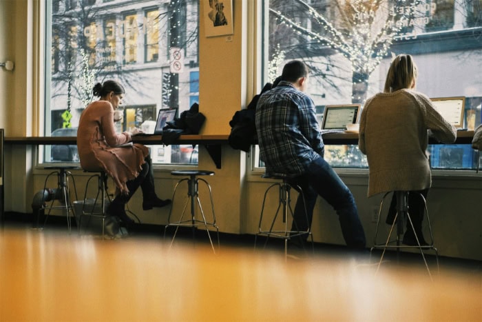 Individuals using laptops inside a cozy cafe setting