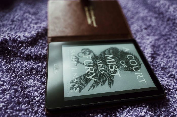 Kindle e reader with a book cover on purple fabric