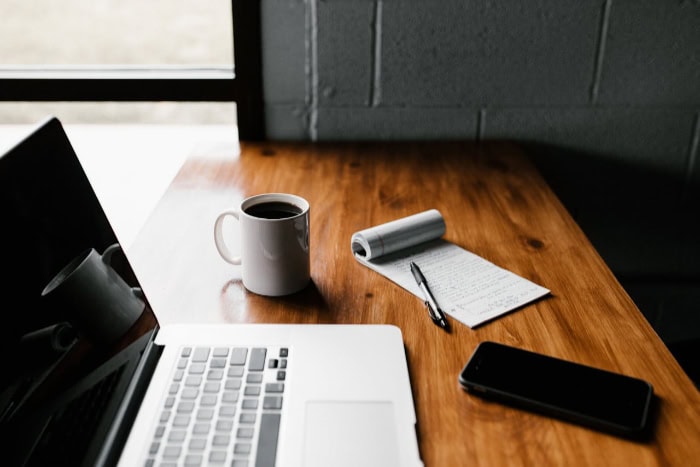 Laptop and coffee on a wooden desk with notes