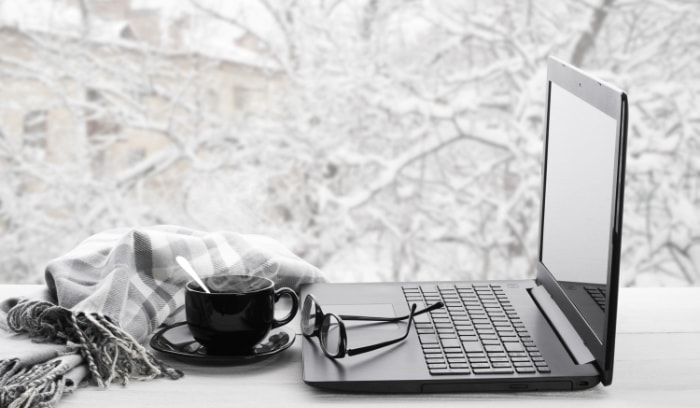 Laptop and glasses on windowsill against snow landscape