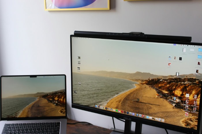 Laptop and monitor showing beach wallpaper on desk