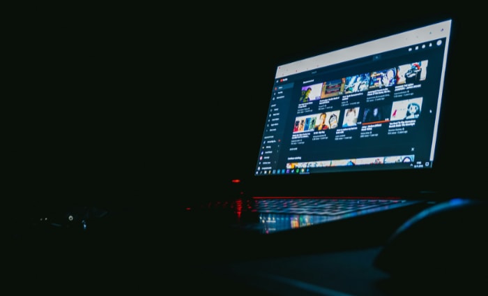 Laptop displaying a video streaming platforms homepage in a dark room