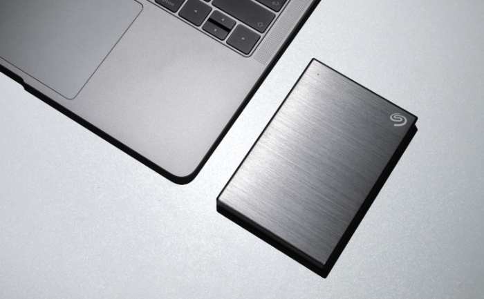 Laptop next to a portable external hard drive on a metallic surface