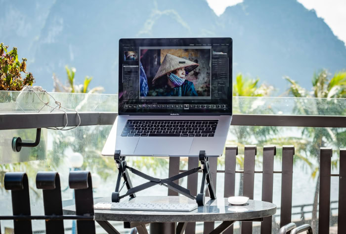 Laptop on balcony overlooking mountains and palm trees