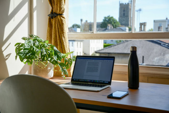 Laptop on wooden desk by a sunny window