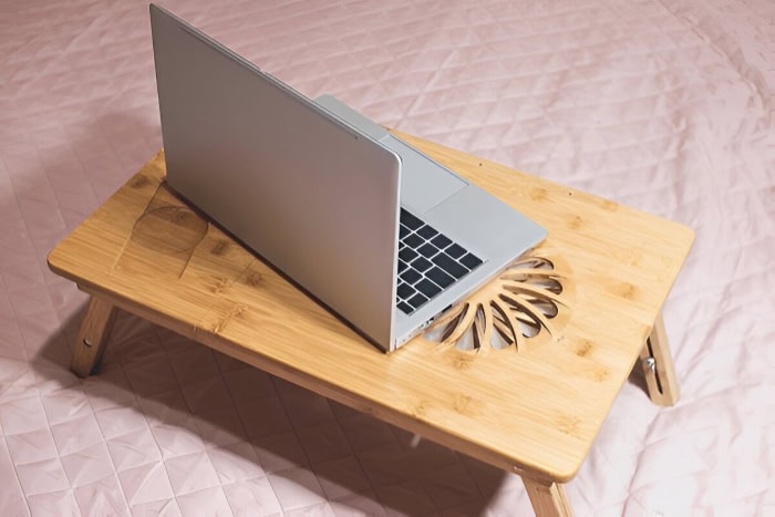 Laptop on wooden lap desk with decorative cutout design