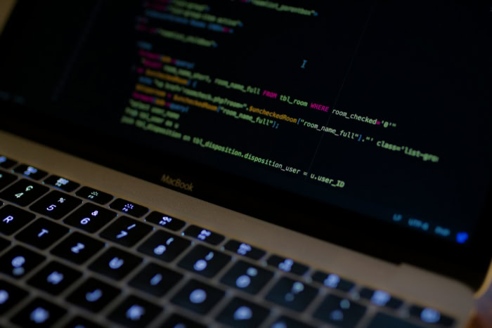 Laptop screen showing detailed SQL and programming code