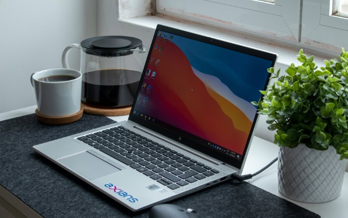 Laptop with colorful desktop background next to coffee and plant